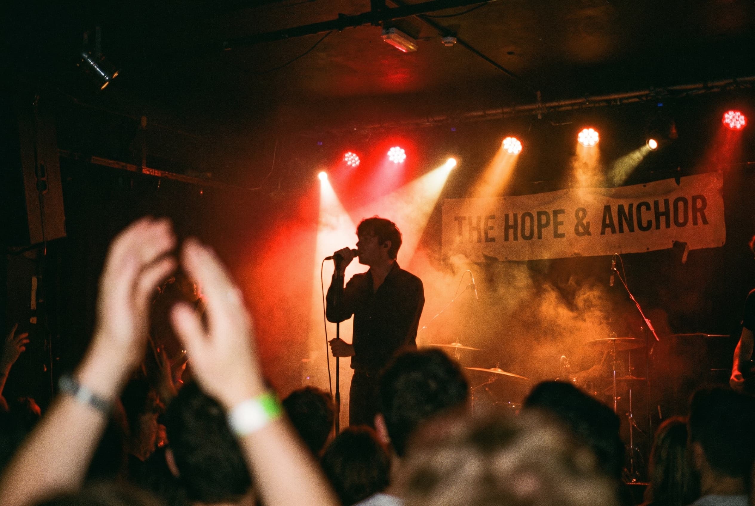 Singer silhouetted under red and amber stage lights in a small London venue