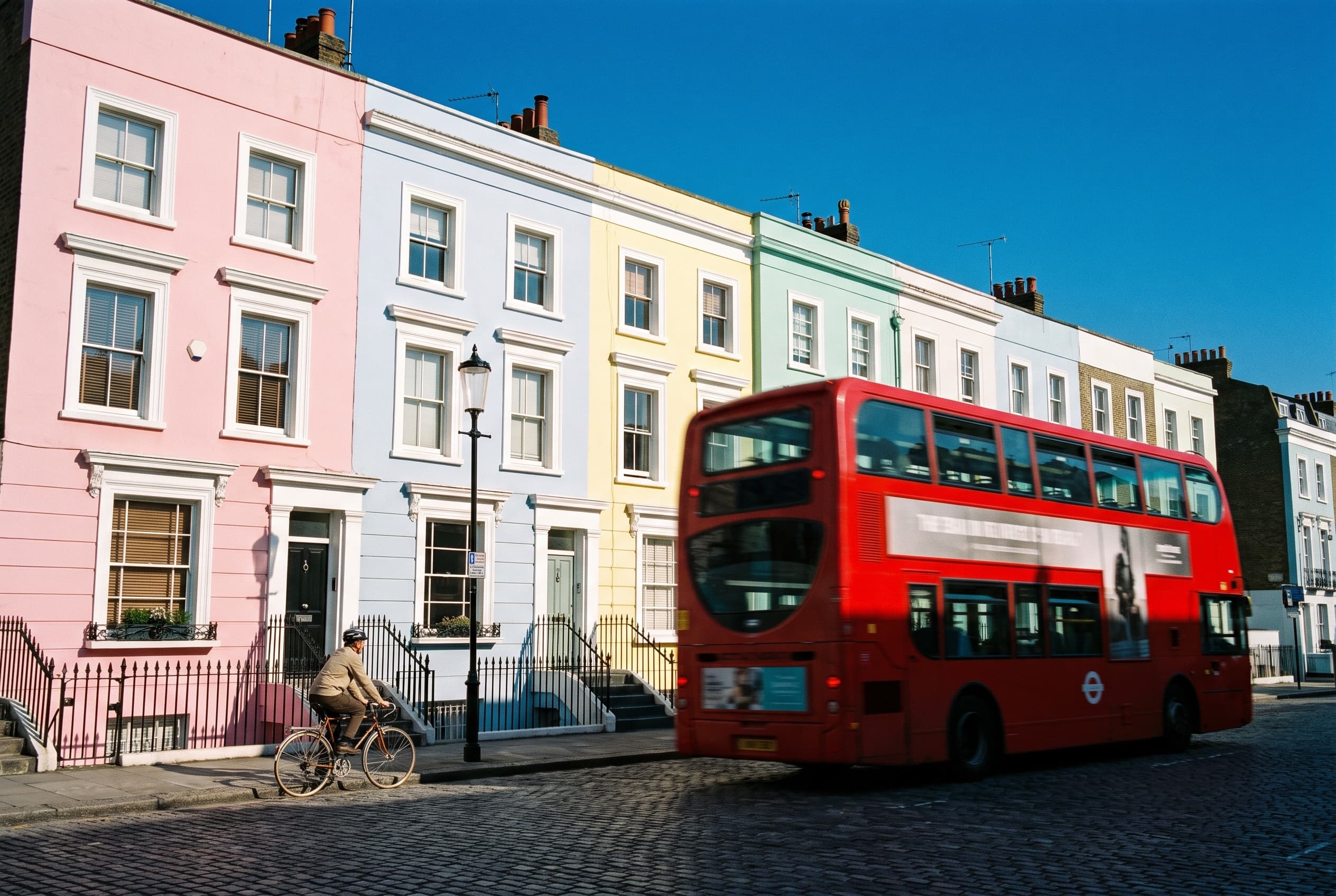 Pastel houses in Notting Hill with a red double-decker bus passing